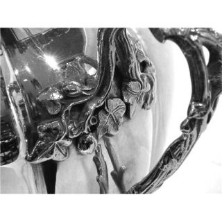   tea urn with two ornate handles bothe the handles and the rim of the